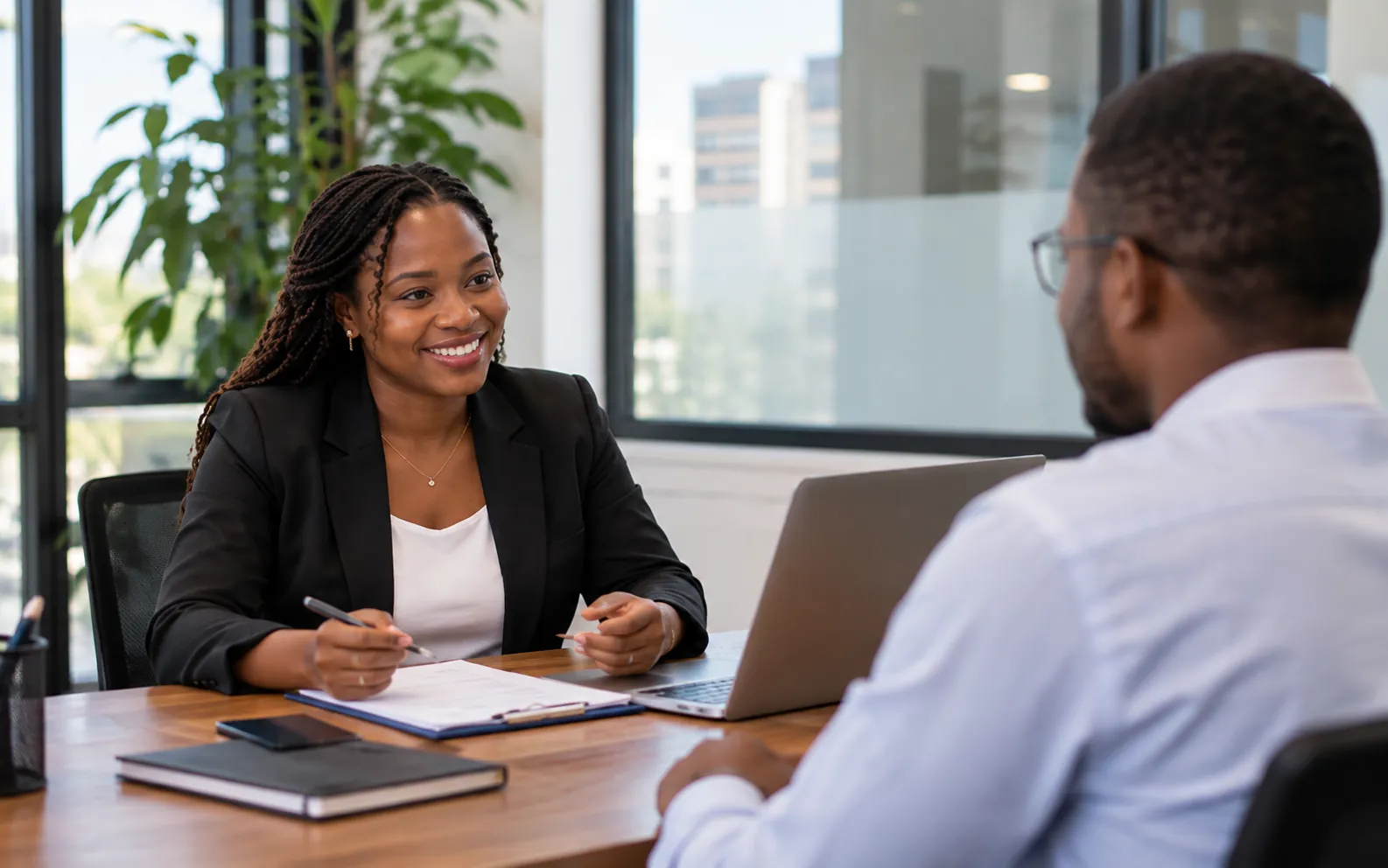 Entrevista de recrutamento: uma profissional sorri à mesa com um candidato
